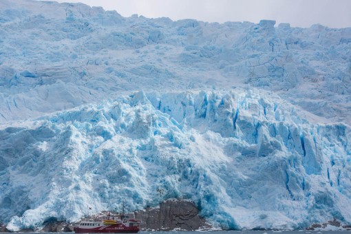Glaciär med vårt fartyg i förgrunden